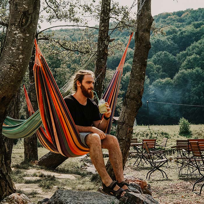 https://www.happyhammockcamper.com/wp-content/uploads/2022/07/bearded-man-hammock-camping-with-a-drink.jpg